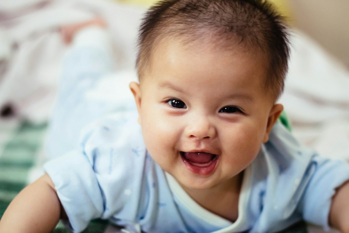 Sample postcard: a baby on his tummy, grinning at the camera
